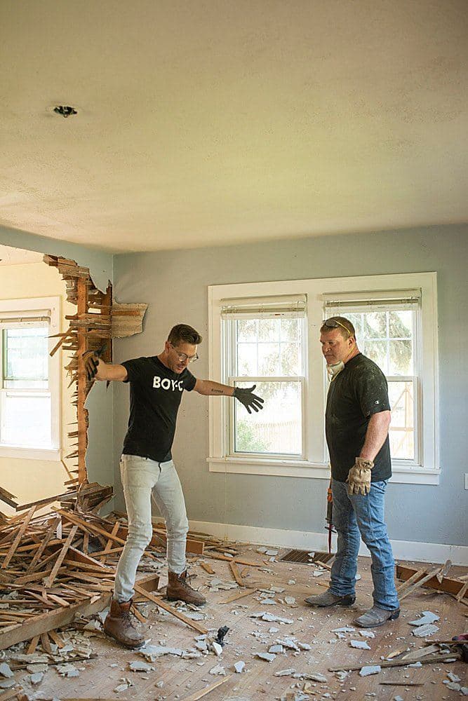 Luke Caldwell gesturing at a demolished wall while Clint Robertson looks on