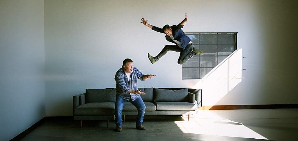 Luke Caldwell jumping while Clint Robertson reacts in a bright living room
