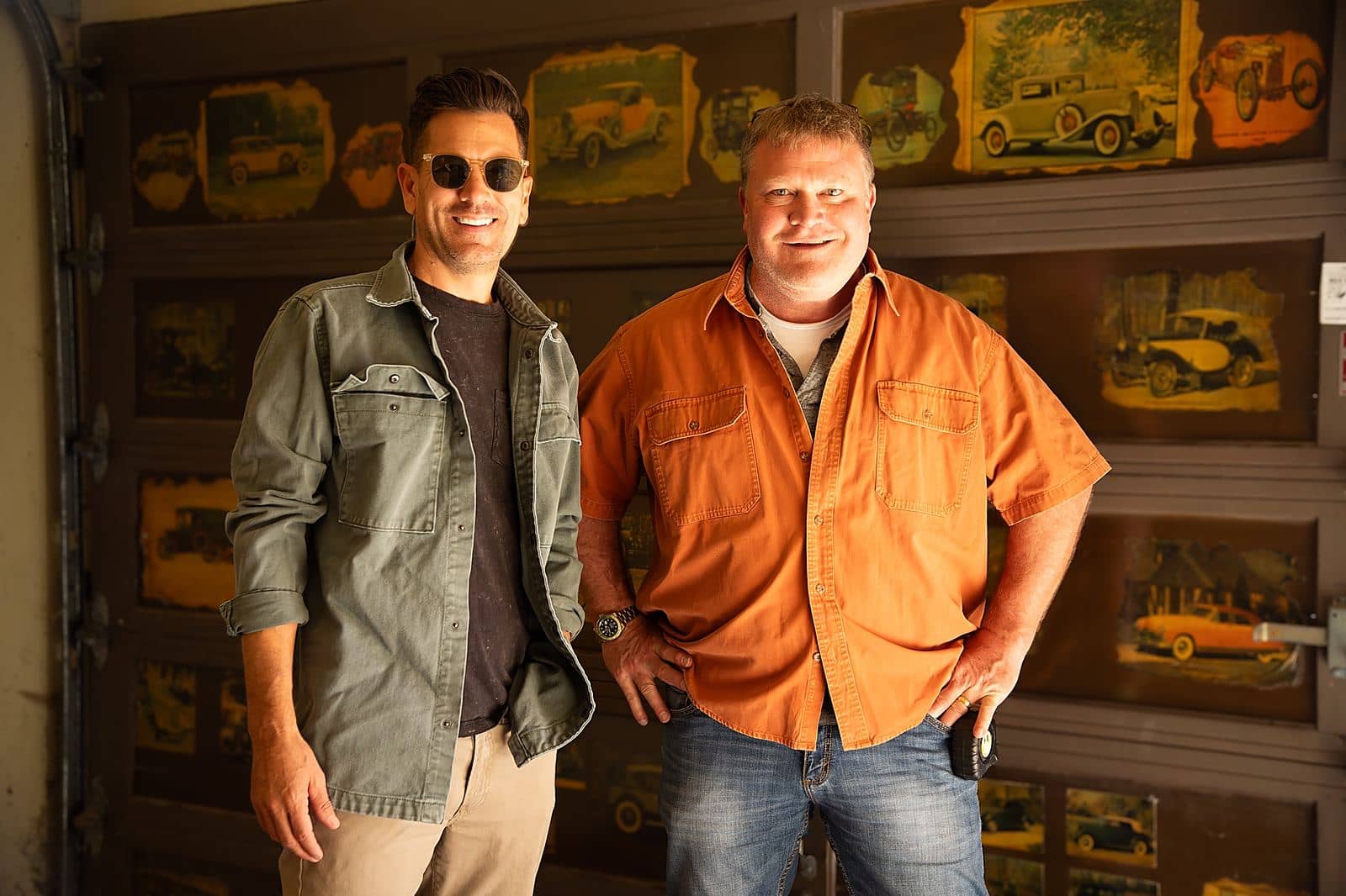 Luke Caldwell and Clint Robertson standing together in a garage lined with vintage car prints