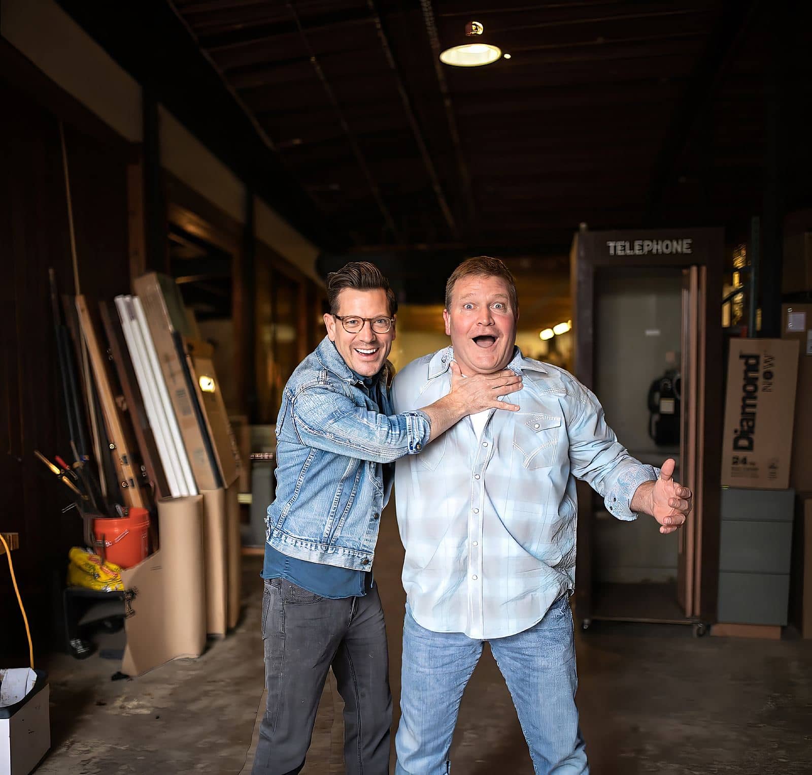 Luke Caldwell with an arm around Clint Robertson in their workshop, both laughing
